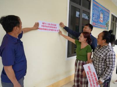 Cử tri bản Trường Sơn, xã Nậm Cắn cùng cán bộ xã dán khẩu hiệu tuyên truyền ngày bầu cử. Ảnh: Bích Huệ - TTXVN