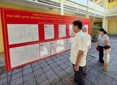 Cử tri theo dõi danh sách, tiểu sử các ứng cử viên được niêm yết công khai tại nhà sinh hoạt cộng đồng. Ảnh: Trần Lê Lâm - TTXVN