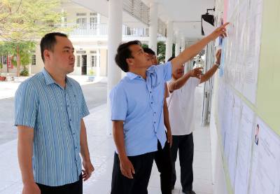 Cử tri vùng biển xã Cà Ná theo dõi danh sách niêm yết các ứng cử viên đại biểu Quốc hội và HĐND tỉnh và xã. Ảnh: Công Thử - TTXVN