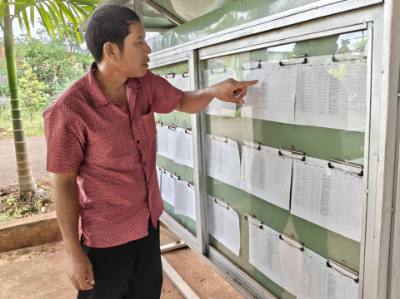 Trưởng thôn Điểu Xu xem thông tin danh sách cử tri tại nhà văn hóa thôn Bình Lợi. Ảnh: K GỬIH-TTXVN 