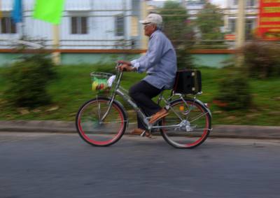 Ông Giảng Văn Phúc đạp xe trên đường Lê Hồng Phong, phường Vị Tân, thành phố Cần Thơ, để tuyên truyền bầu cử. Ảnh: Duy Khương – TTXVN