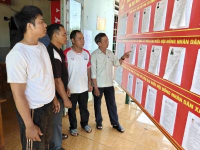 Đảng viên và cử tri thôn Sơn Trung (xã Phú Nghĩa) tìm hiểu tiểu sử đại biểu ứng cử. Ảnh: K GỬIH-TTXVN 