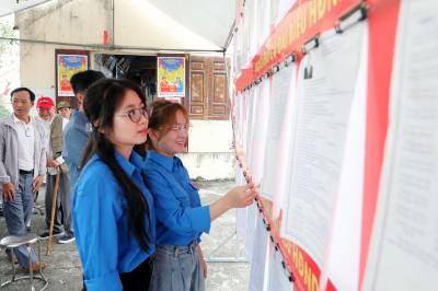 Các công nhân, đoàn viên thanh niên nghiên cứu thông tin ứng cử viên trước khi bầu cử. Ảnh: Đại Nghĩa - TTXVN