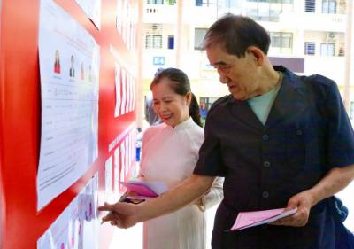 Cử tri tìm hiểu thông tin các ứng cử viên trước khi thực hiện quyền bầu cử sáng 15/3. Ảnh: Lan Anh/TTXVN phát