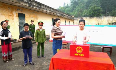Người bị tạm giữ, tạm giam thực hiện quyền bầu cử bằng việc bỏ phiếu vào hòm phiếu tại điểm bầu cử được tổ chức trong khuôn viên Trại tạm giam số 2 - Công an tỉnh Tuyên Quang. Ảnh: Minh Tâm - TTXVN